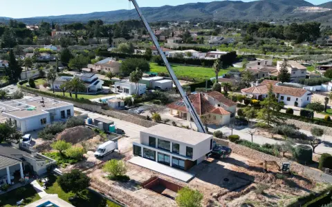 Construcción moderna en zona residencial, mostrando la diferencia entre urbano y urbanizable con grúa y excavadora.