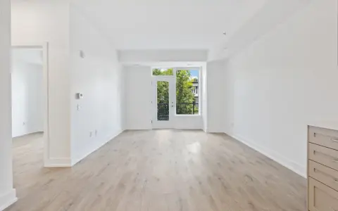 Salón luminoso con suelo de madera clara y puerta acristalada que da a un balcón. Ideal para vender piso heredado antes de 5 años.
