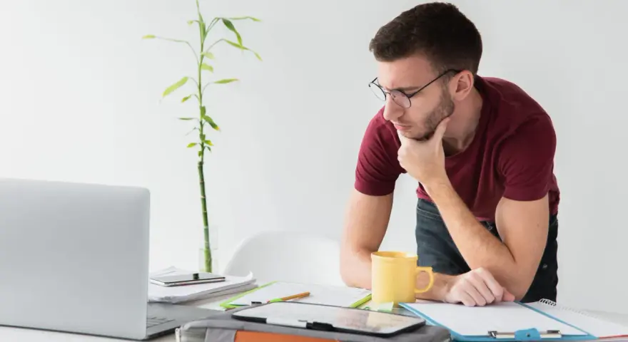 Joven autónomo reflexiona en su escritorio. Lo cotizado como autónomo cuenta para el paro, una tranquilidad para su futuro.