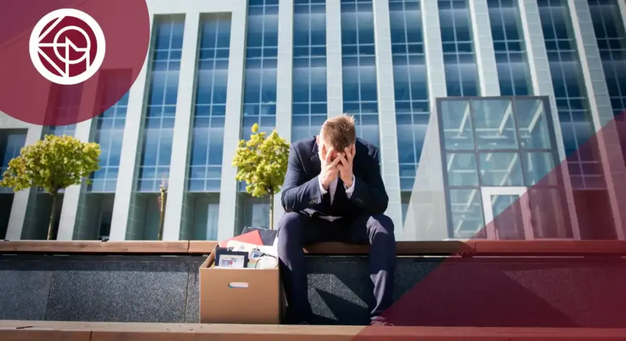 Hombre con caja de pertenencias, sentado frente a un edificio. ¿Me pueden despedir si estoy cubriendo una baja?