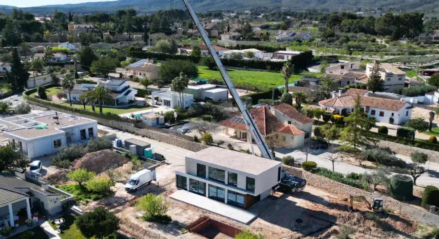 Construcción moderna en zona residencial, mostrando la diferencia entre urbano y urbanizable con grúa y excavadora.
